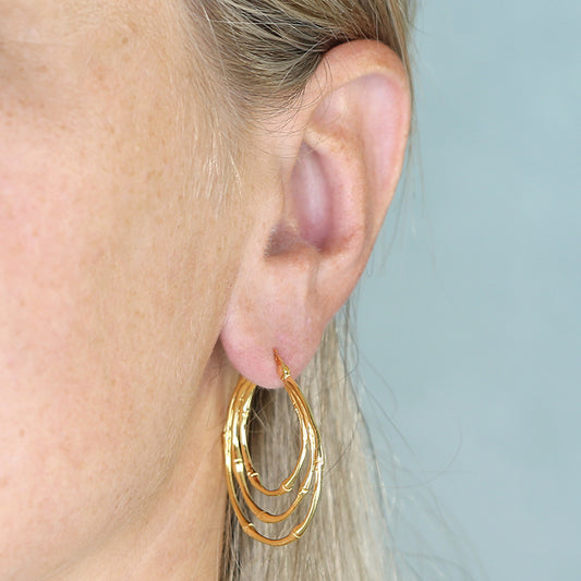 Gold-plated triple bamboo hoop earrings worn